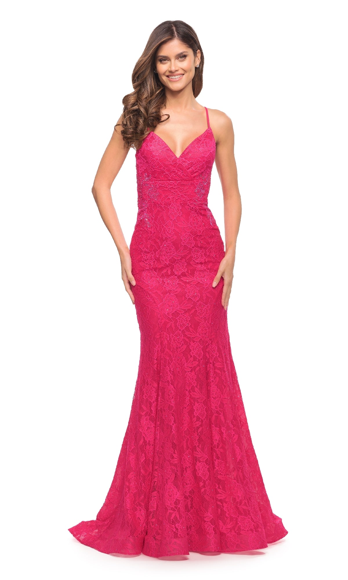 A woman models the La Femme 30690 Hot Pink Lace Prom Dress—a sleeveless, floor-length gown with thin straps and an elegant open back—against a white background.