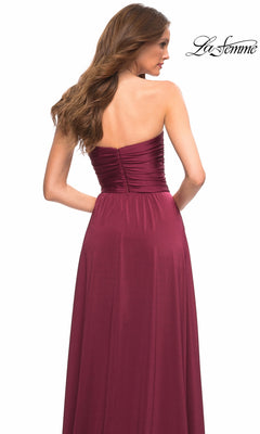 A woman stands with her back to the camera in the Long Prom Dress: La Femme 30700, featuring a strapless ruched bodice and a flowing skirt. The “La Femme” logo is top right.