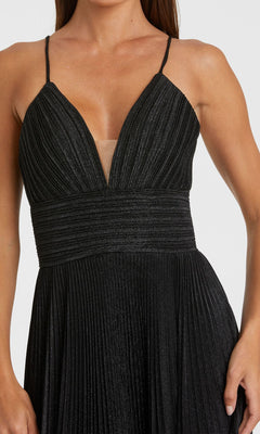 A woman wears the Pleated Empire-Waist Long A-Line Prom Dress 30725, a sleeveless black gown with a deep V-neckline, fitted waist, and elegant pleats—perfect for a chic prom look.