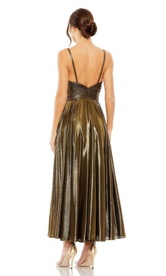 A woman faces away, wearing the Mac Duggal 30761 tea-length wedding-guest dress in metallic gold with thin straps and nude high heels.