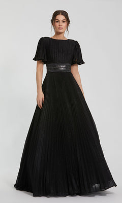 A woman wears the Mac Duggal 30776, a short sleeve long formal dress in pleated black with a fitted waist, standing against a plain light background.