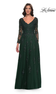 A woman wears a La Femme 30795 emerald green V-neck formal gown with sheer sleeves and a tulle A-line skirt detailed with intricate, beaded lace appliques.