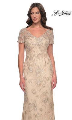 La Femme 30798 is a floor-length, nude-colored V-neck formal dress with short sleeves and intricate silver floral embroidery and sequins.