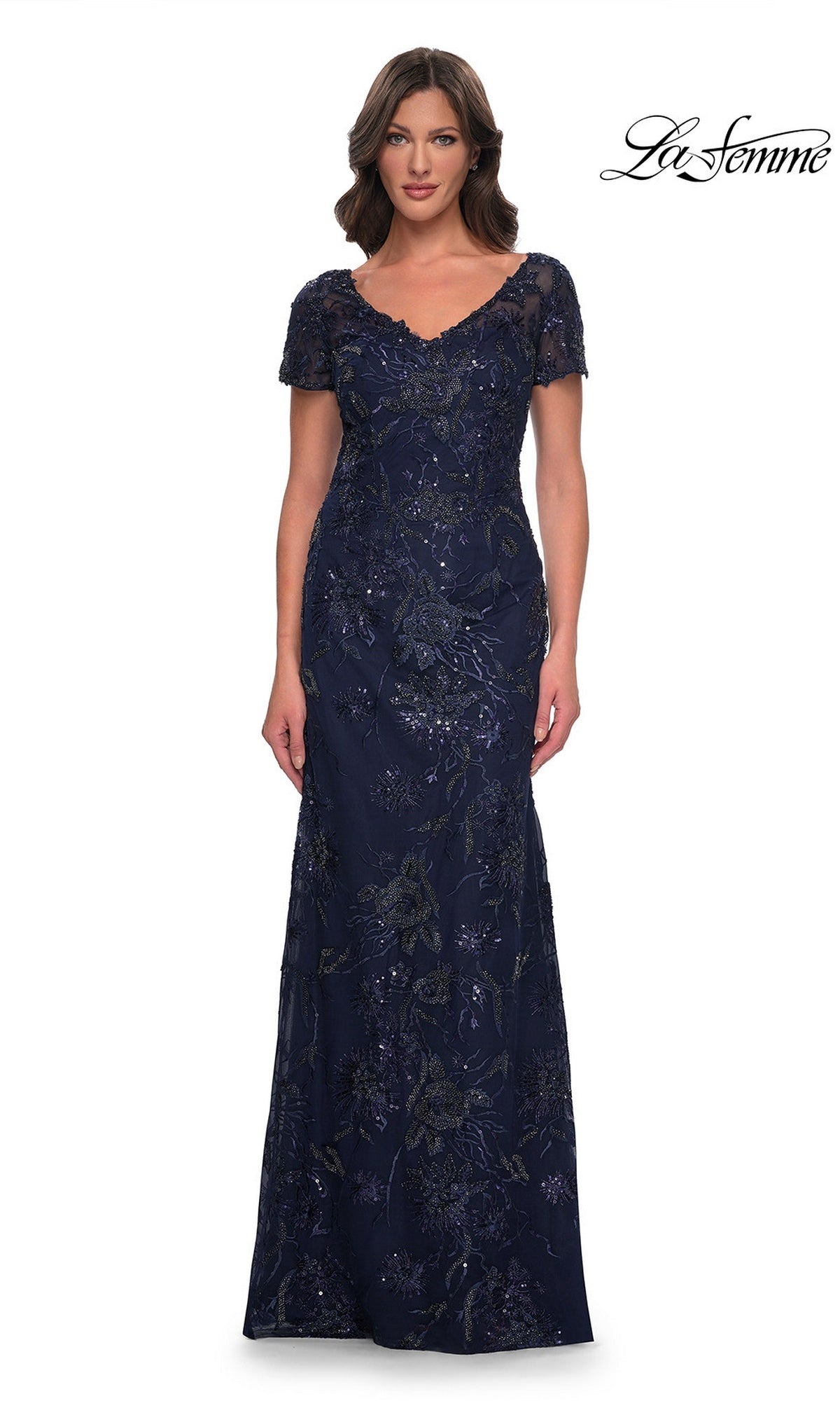 A model wearing a navy La Femme 30798 long formal dress with a V-neck, short sleeves, and floor-length floral beadwork embroidery.