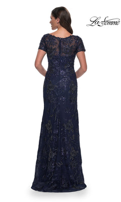 Back view of a woman in a Long Formal Dress: La Femme 30798, a navy blue v-neck gown with short sleeves, a sheer neckline, and intricate sequin floral embroidery.