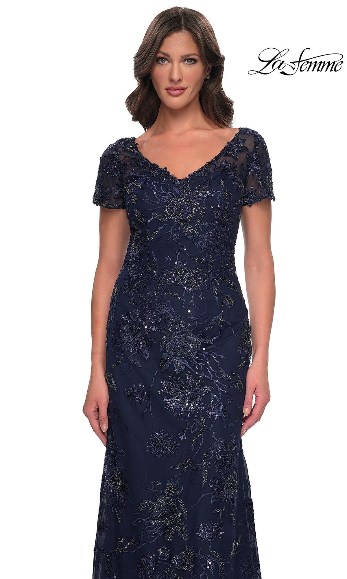 A woman wearing a Long Formal Dress: La Femme 30798 in navy blue, featuring short sleeves, an embellished V-neckline, and intricate floral beadwork.