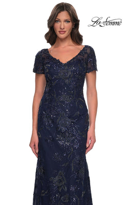 A woman wearing a Long Formal Dress: La Femme 30798 in navy blue, featuring short sleeves, an embellished V-neckline, and intricate floral beadwork.