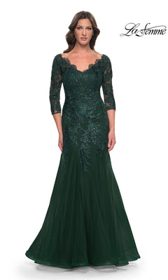 A woman wearing a Long Formal Dress: La Femme 30823, an emerald green modest lace mermaid gown with a floor-length silhouette, three-quarter sleeves, a V-neckline, and sequined floral embroidery.