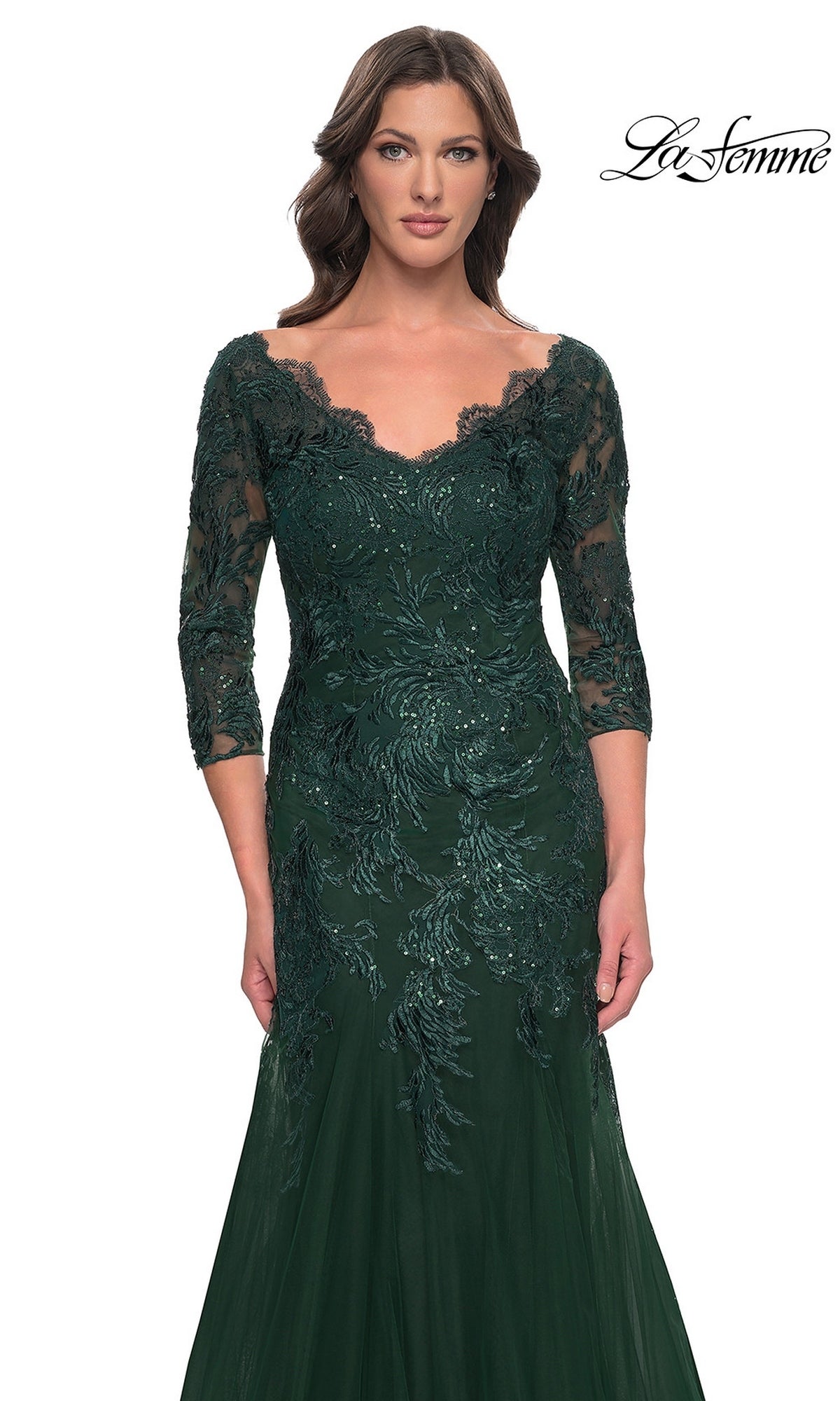 A woman wears the Long Formal Dress: La Femme 30823, a dark green, modest lace mermaid dress with a V-neckline, three-quarter length sleeves, and intricate sequin detailing on the bodice.