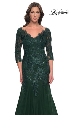 A woman wears the Long Formal Dress: La Femme 30823, a dark green, modest lace mermaid dress with a V-neckline, three-quarter length sleeves, and intricate sequin detailing on the bodice.