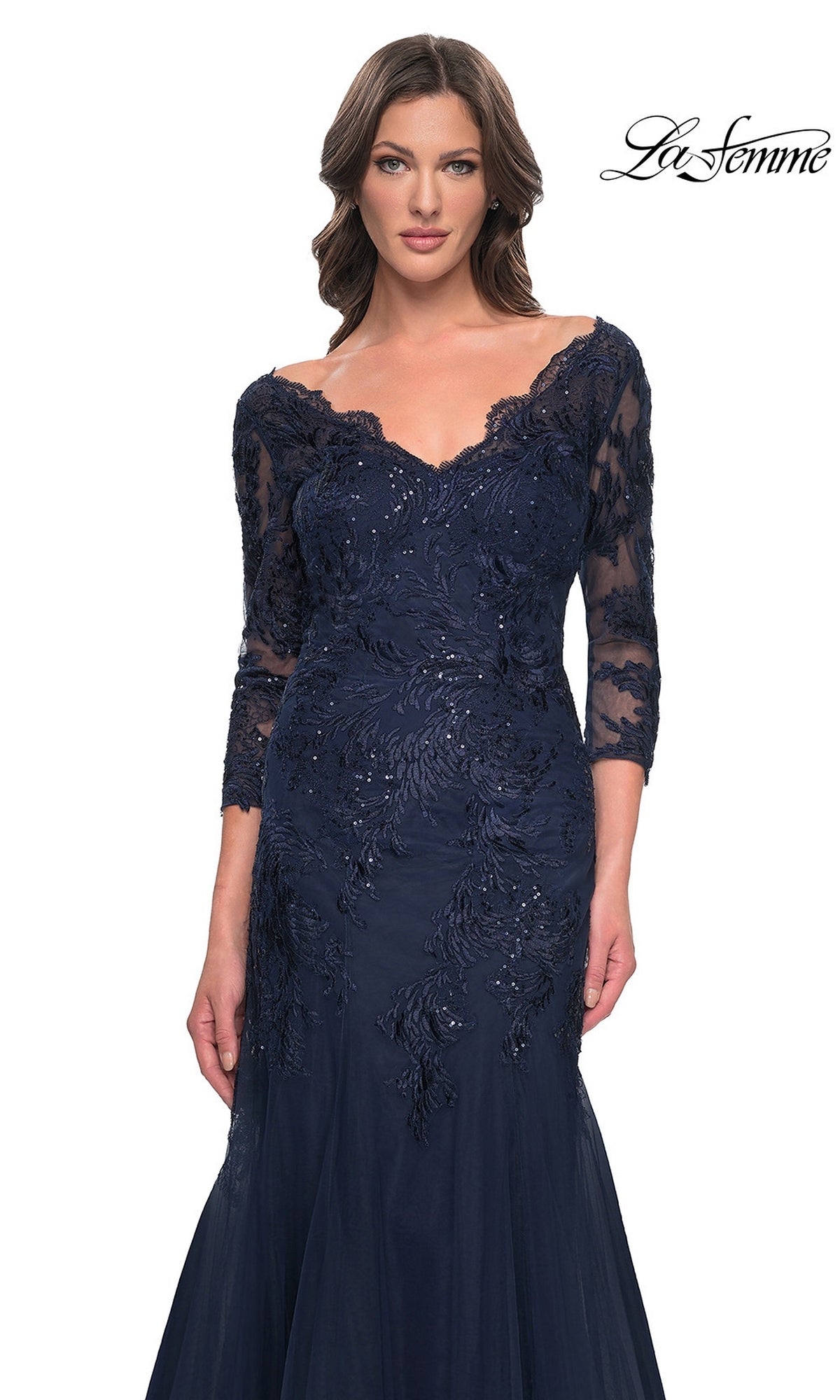A woman wears the Long Formal Dress: La Femme 30823, a navy blue, off-the-shoulder gown with three-quarter lace sleeves and sequin floral embroidery.
