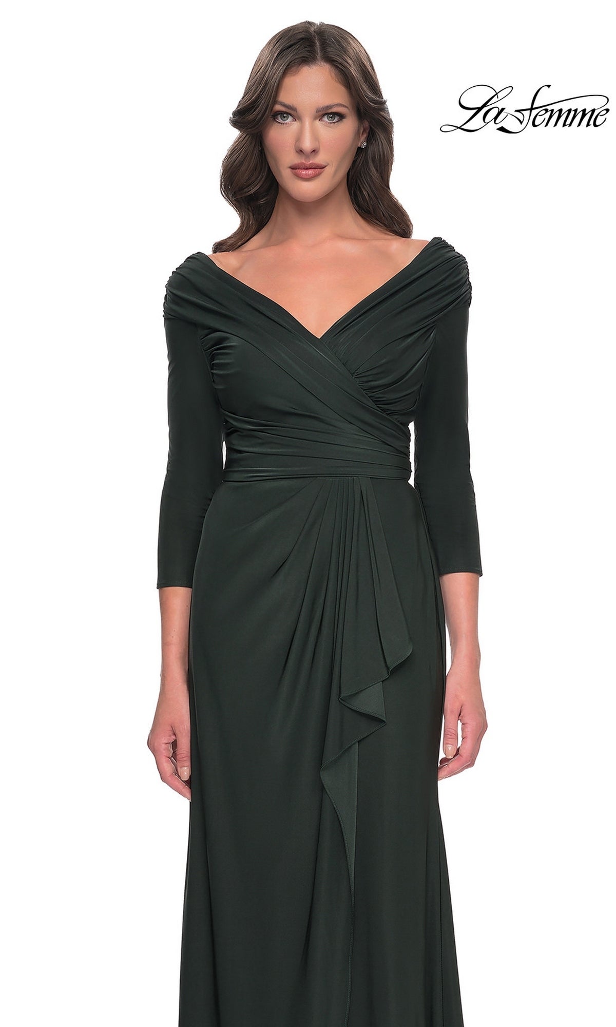 A woman wears a dark green Long Formal Dress: La Femme 30845, featuring a draped, off-the-shoulder V-neckline and three-quarter length sleeves.