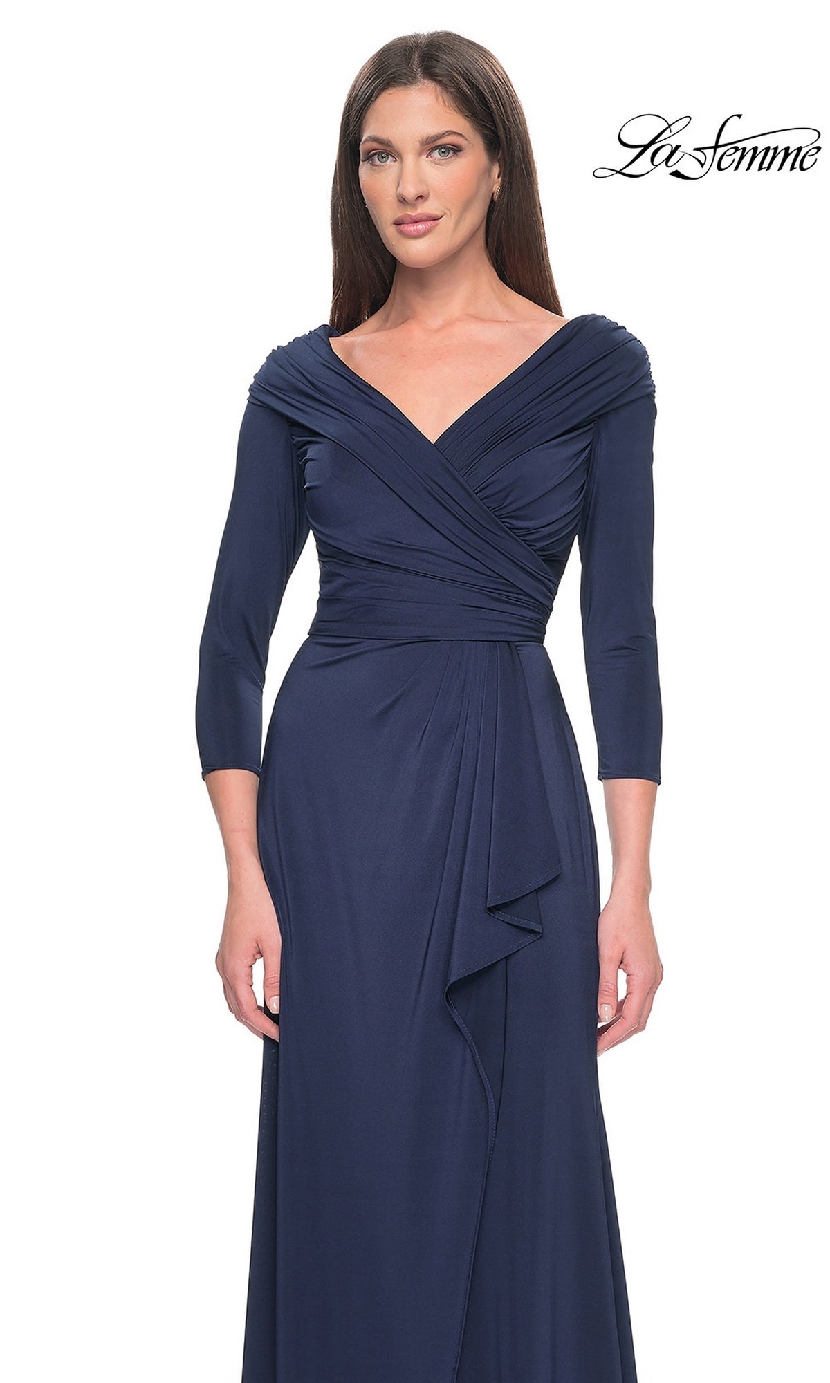 A woman wears a navy blue, long-sleeved La Femme 30845 formal dress featuring an off-the-shoulder, draped v-neckline and a side-slit skirt.
