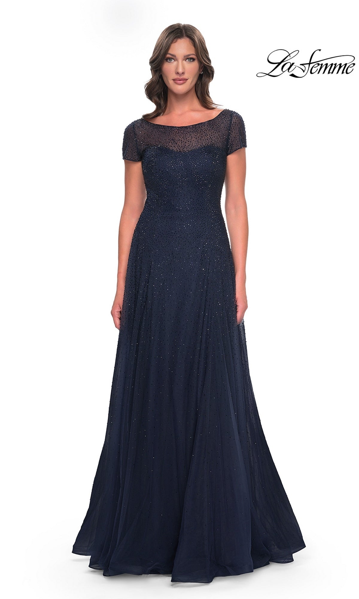 A woman wears a navy Long Formal Dress: La Femme 30852, featuring a beaded bodice with a sheer illusion neckline and cap sleeves.