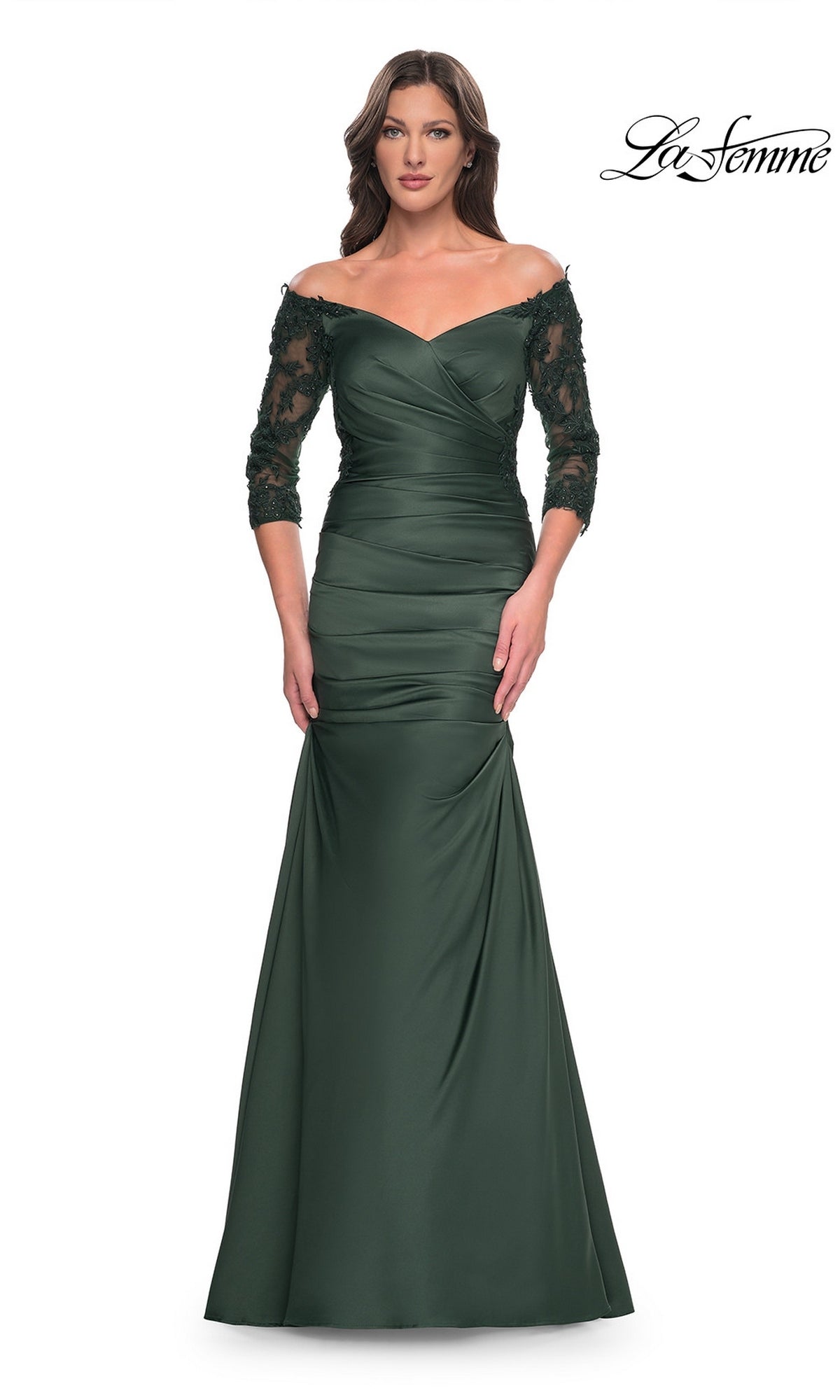 A model wears an emerald Long Formal Dress: La Femme 30853, an off-the-shoulder satin gown with three-quarter length lace sleeves, a ruched bodice, and a trumpet skirt.