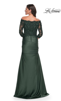 Woman wearing a La Femme 30853, an off-the-shoulder, dark green floor-length gown with a lace bodice, three-quarter length lace sleeves, and a draped trumpet skirt.