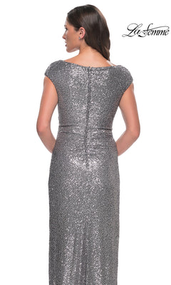 A woman wearing a Long Formal Dress: La Femme 30865, a long, cap-sleeve silver sequin gown with a sheath silhouette and a ruched back.