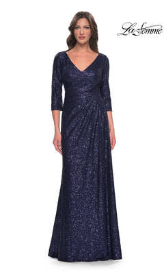 A woman wears a navy Long Formal Dress: La Femme 30879 featuring a V-neck, three-quarter length sleeves, and a floor-length silhouette.