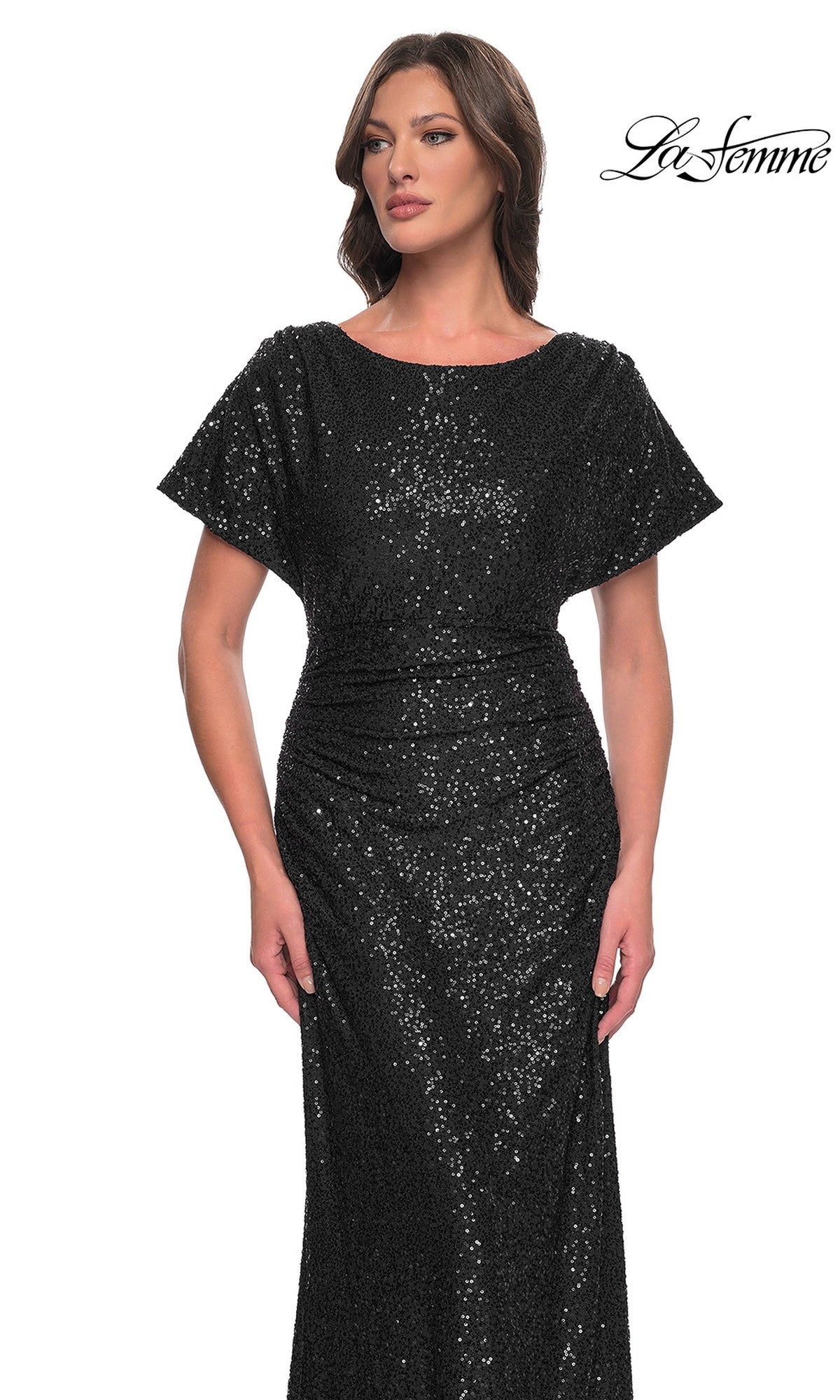 A woman wears the La Femme Short-Sleeve Sequin Formal Dress 30885, featuring a fitted silhouette and floor-length style, standing against a white background with the 