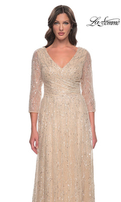 A woman wears a tan, v-neck Long Formal Dress: La Femme 30911, a champagne formal gown with three-quarter sleeves and all-over vertical sequin and bead embellishments.