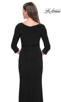 A woman faces away from the camera in the La Femme Sleeved Simple Jersey Formal Dress 30967, a long-sleeved, floor-length gown with a fitted waist. The La Femme logo is displayed in the top right corner.