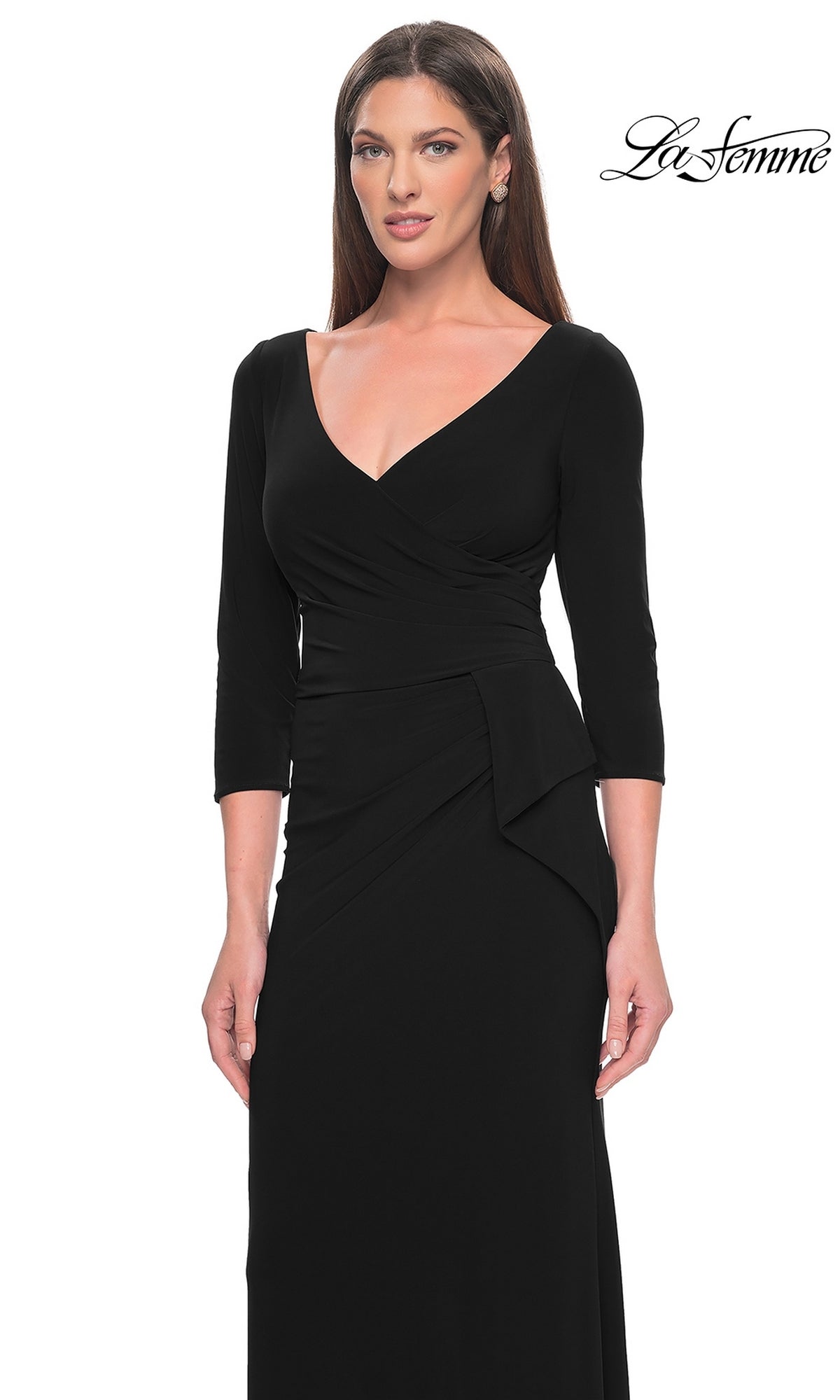 A woman stands against a white background wearing the La Femme Sleeved Simple Jersey Formal Dress 30967, a fitted long black dress with three-quarter sleeves and a V-neck. The 