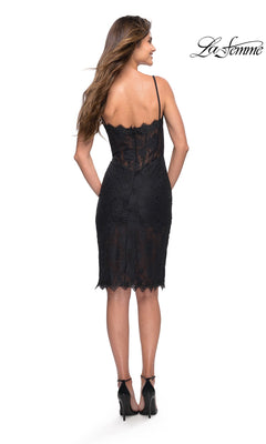A woman with long wavy hair, shown from the back, wears the La Femme 30989 black lace knee-length party dress featuring a bodycon fit and high heels, set against a white background. The “La Femme” logo appears in the top right corner.
