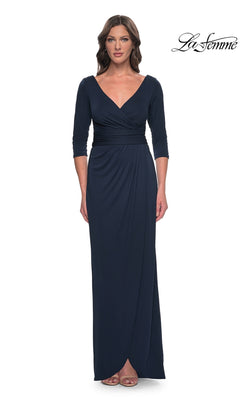 A woman wears a navy Long Formal Dress: La Femme 31014, featuring a long-sleeved, faux wrap design with a V-neckline and a modest formal silhouette.