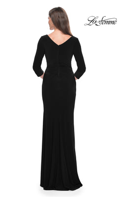 A woman stands with her back to the camera in a La Femme Long-Sleeve Fitted Formal Dress 31020, black with a v-neck and three-quarter sleeves, against a white background. The "La Femme" logo appears in the top right corner.