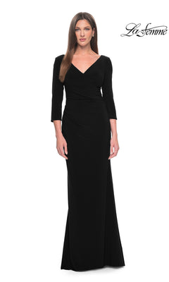 Woman wears the La Femme Long-Sleeve Fitted Formal Dress 31020 in black, featuring three-quarter sleeves and a v-neck in sleek jersey fabric, standing against a plain white background with the La Femme logo at the top right.
