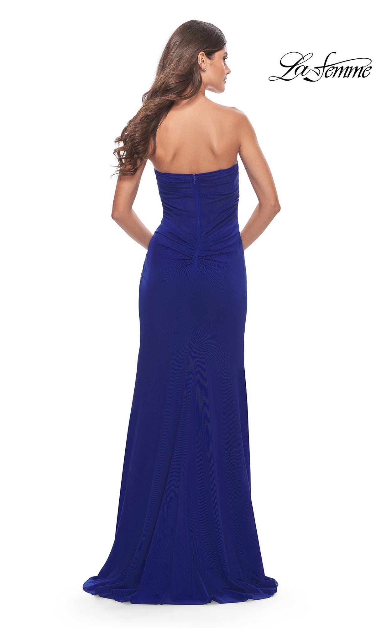 A woman with long brown hair is shown from the back wearing the Sheer-Bodice Strapless Long La Femme Prom Dress in royal blue, floor-length, with the La Femme logo in the top right corner.