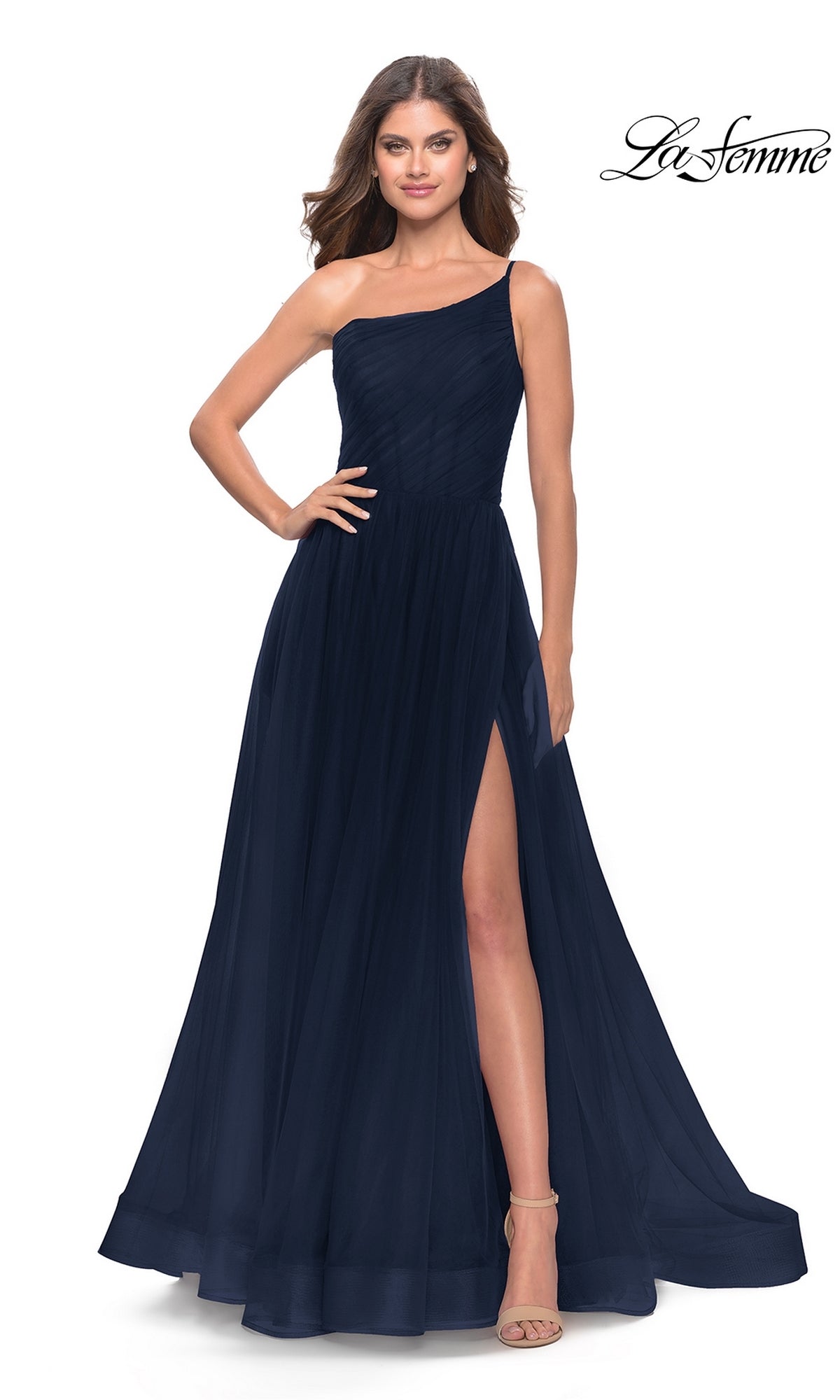 A woman stands confidently with one hand on her hip, wearing the One-Shoulder Sheer-Bodice Prom Ball Gown 31069—floor-length, dark navy, with a high leg slit.