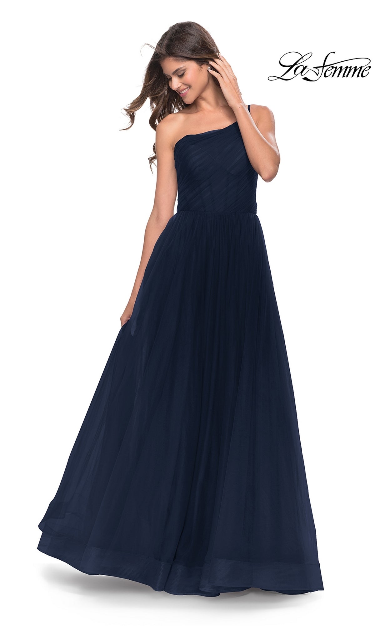 A woman smiles as she looks down, wearing the La Femme One-Shoulder Sheer-Bodice Prom Ball Gown 31069—a floor-length, navy blue formal dress featuring a fitted bodice and full skirt.
