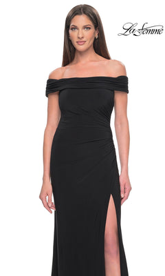 A woman wears a black off-the-shoulder Long Formal Dress: La Femme 31086, featuring a high-leg slit and a floor-length hem.