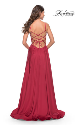 A woman faces away from the camera in the Corset-Back La Femme Long A-Line Prom Dress 31105, a floor-length red gown with thin straps, a crisscross corset back, and a flowing A-line skirt.