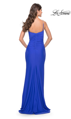 Woman in a floor-length, fitted royal blue La Femme Wrap-Style Long Prom Dress 31107 with thin straps and ruched back, facing away from the camera. "La Femme" logo appears in the top right corner.