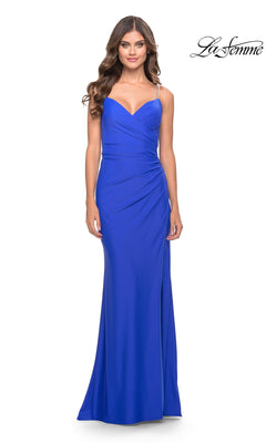 A woman wears the La Femme Wrap-Style Long Prom Dress 31107 in fitted, floor-length royal blue with spaghetti straps, slight waist ruching, and a sweetheart neckline. The La Femme logo is displayed in the top right corner.