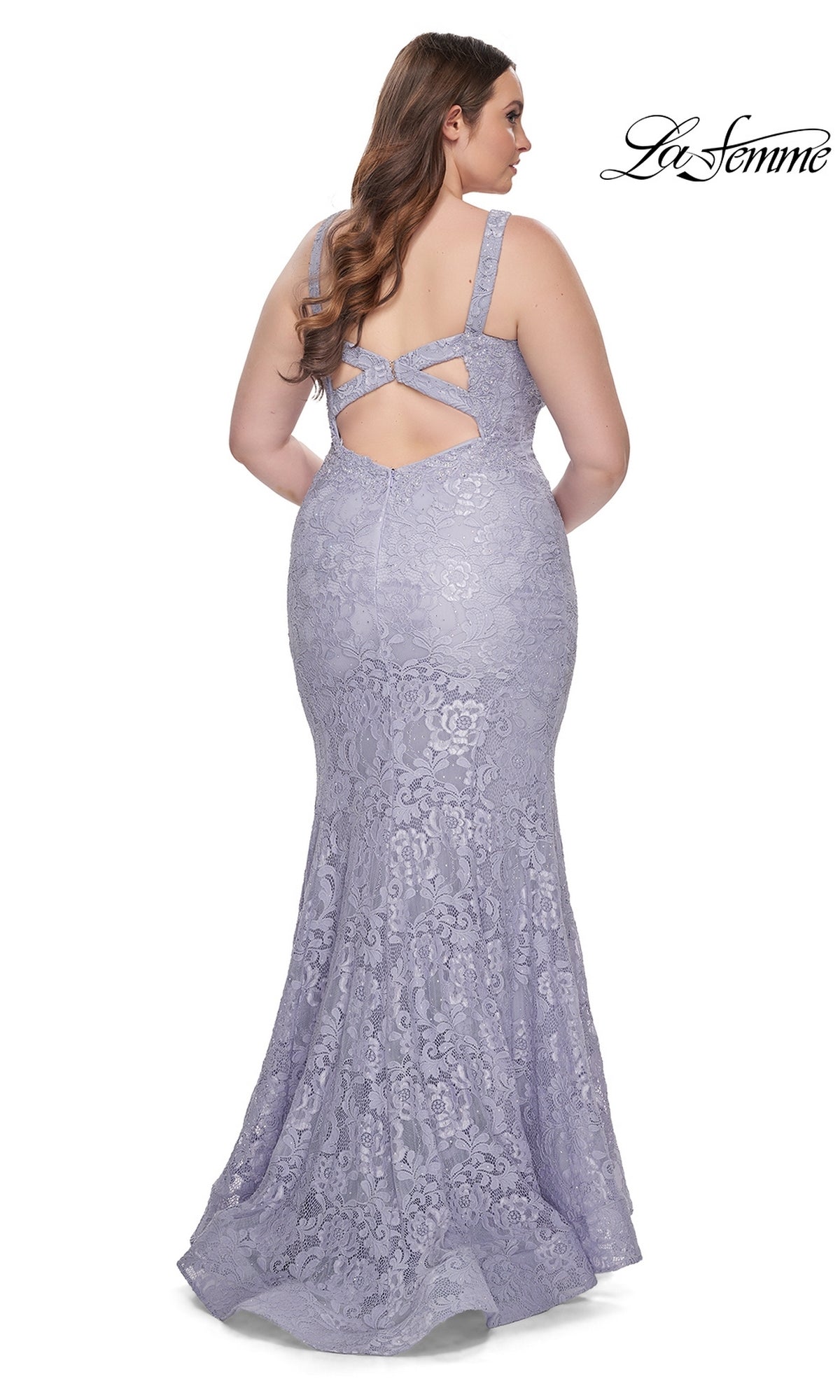 A woman wears the La Femme Long Prom Dress 31118 in fitted lavender lace with a low back and crisscross straps, standing against a white background.