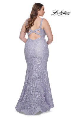 A woman wears the La Femme Long Prom Dress 31118 in fitted lavender lace with a low back and crisscross straps, standing against a white background.