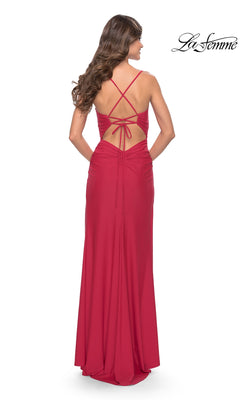 A woman models the La Femme Strappy-Back Long Ruched Prom Dress 31127 in red, featuring a backless design with crisscross straps and ruched details. The La Femme logo appears in the top right corner.