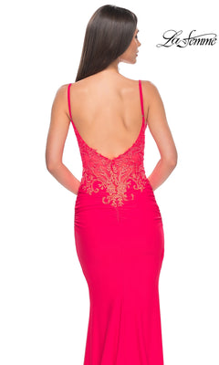 A woman is seen from behind wearing the La Femme Sheer-Waist Long V-Neck Prom Dress 31128 in bright pink, featuring a gold embroidered-lace bodice; the "La Femme" logo appears in the top right corner.