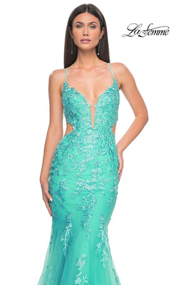 Woman in the La Femme Long Lace Mermaid Prom Dress 31133—turquoise, fitted, with floral embroidery, spaghetti straps, side cutouts, and a sleek silhouette—stands against a white background featuring the "La Femme" logo.