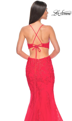 A woman models the La Femme Long Lace Mermaid Prom Dress 31133, featuring thin crisscross straps and elegant lace detailing, set against a white background with the "La Femme" logo in the top right corner.