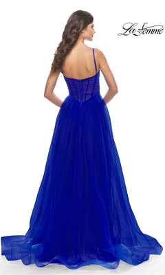 A woman models the Sheer-Waist La Femme Long Prom Ball Gown 31147 in royal blue, showing the elegant back details of the floor-length formal dress with spaghetti straps and a sheer overlay. The La Femme logo is visible in the corner.