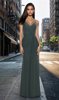 A woman wears the Twist-Front La Femme Long Formal Dress 31169 in Dark Emerald, standing on a sunny city street lined with buildings.