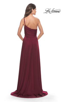 A woman faces away from the camera in a floor-length, burgundy One-Shoulder Long La Femme Formal Dress 31170, featuring subtle pleats and a slight train. The La Femme logo appears in the corner.