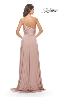 A woman faces away, wearing the One-Shoulder Long La Femme Formal Dress 31170 in blush pink. The gown features a ruched bodice and flowing skirt, making it a stunning choice for prom. The La Femme logo is visible in the upper right corner.