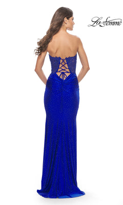 Woman in the Lace-Bodice Strapless La Femme Prom Dress 31180, royal blue, floor-length with a lace-up back and subtle sparkles, stands with her back to the camera.