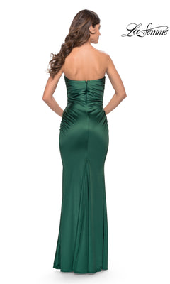 A woman models the Simple Strapless Long La Femme Prom Dress 31189—an emerald green satin gown with side ruching and a fitted, floor-length silhouette, shown elegantly from the back.