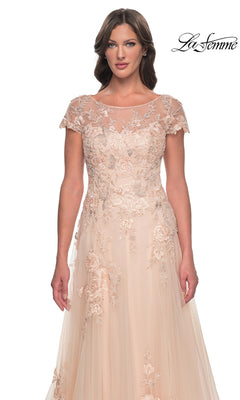 A woman wearing the Long Formal Dress: La Femme 31198, a champagne formal dress featuring a blush-colored A-line tulle skirt, a sheer illusion neckline, cap sleeves, and floral embroidery.